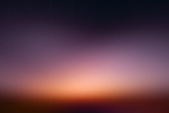 Blurry sunset sky with gradient of deep purple to orange and dark foreground