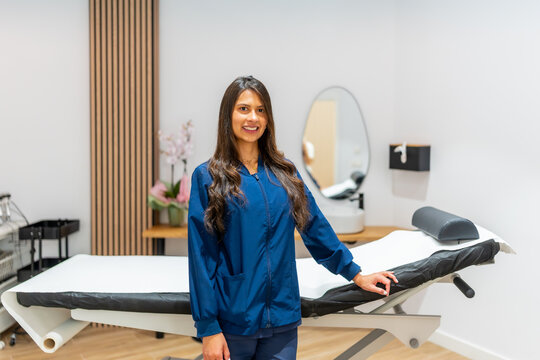 Smiling woman working at aesthetic clinic presenting treatment room