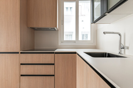 Corner kitchen counter with black granite sink, chrome faucet, oak cabinetry, and window overlooking neighboring building facade.