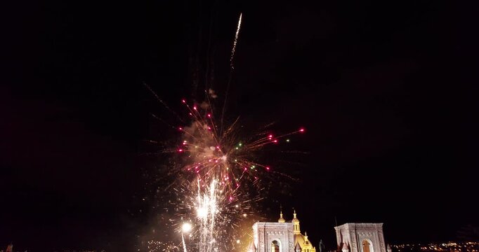 beautiful night drone footage of the immaculate conception cathedral in cuenca ecuador illuminated during the amazing corpus christi celebration with colorful fireworks exploding in the black city sky