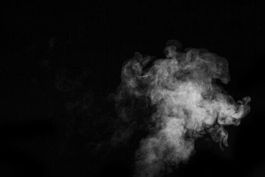 Fragment of white hot curly steam smoke isolated on a black background. Abstract background, design element