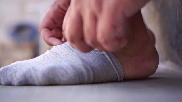 man putting on cotton socks, feet close up, dressing and morning routine concept.