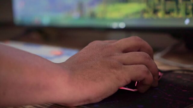 hand using gaming mouse with RGB lighting on desk. Computer gaming setup, technology lifestyle, close-up stock footage.