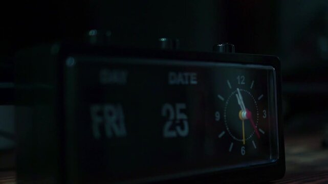 finger pressing button on analog alarm clock, dark room setting, morning wake up and time management concept.