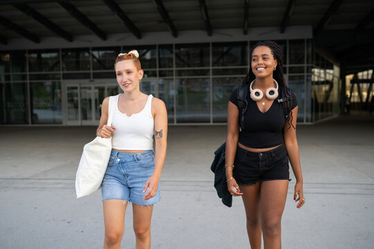 Two white and African American women walk casually outdoors