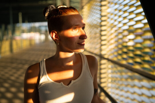 Young white woman stands in sunlight casting patterned shadows