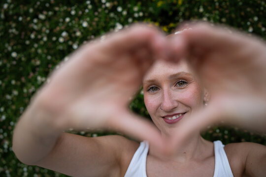 A white woman forms a heart shape with her hands