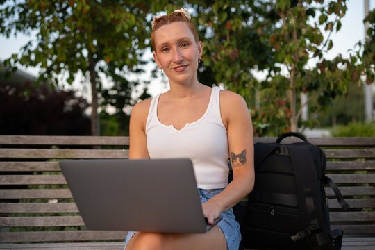 White Woman working on laptop outdoors on a bench