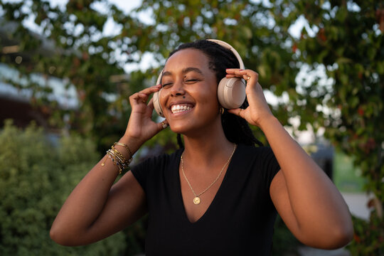 A African American woman enjoys music outdoors with headphones