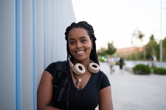 A young African American woman with headphones smiles