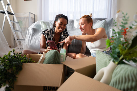 Two African American and white women unpack boxes and enjoy a joyful