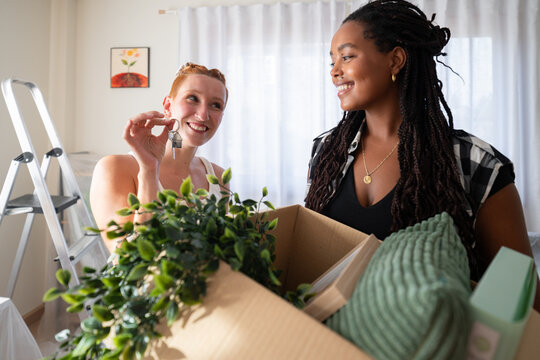 Two African American women happily unpack moving boxes and hold keys