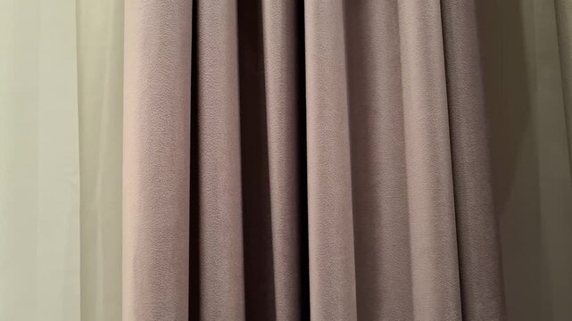 Samples of dense fabric drapes and sheer tulle curtains hanging indoors. Home textile design, window treatment decoration, cozy room interior styling.