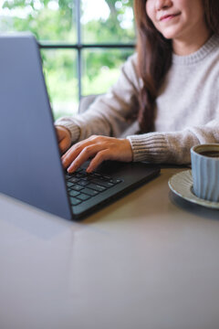 Vertical closeup image of a woman working and typing on laptop computer