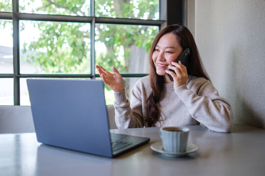 Portrait image of a businesswoman talking on mobile phone while working on laptop computer