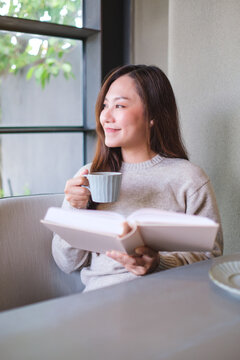 Vertical portrait image of a woman reading a book and drinking coffee