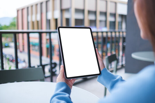 Mockup image of a woman holding digital tablet with blank white desktop screen in cafe