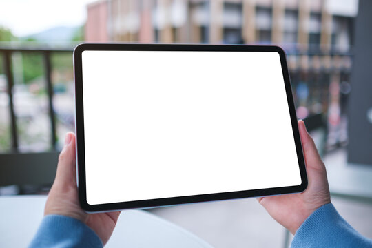 Mockup image of a woman holding digital tablet with blank white desktop screen in cafe