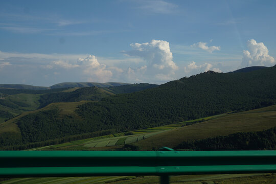 Rolling mountain landscapes under bright blue sky with fluffy clouds
