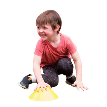 Happy little boy playing with yellow training cone isolated on transparent background. Child exercising or learning sport agility. Concept of active childhood, physical development and fun.