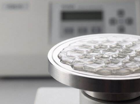 Macro shot of liquid polymer resin forming hexagonal honeycomb waves on metallic ultrasonic vibration platform in laboratory