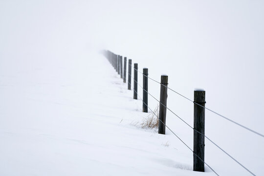 Minimalist Wooden Fence Vanishing into White Fog and Snow