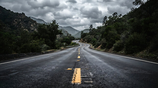A winding asphalt road stretches through a mountainous landscape under a dramatic, cloudy sky, flanked by dark green trees.