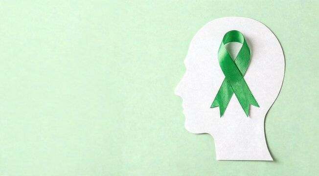 Green ribbon placed on paper cutout of human head to promote mental health awareness