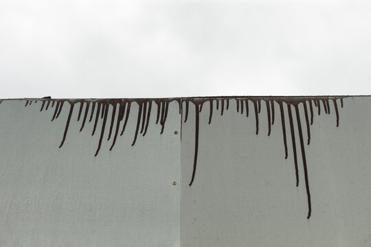 Black paint drips across concrete wall, evoking gritty urban decay with long vertical streaks, weathered surface texture, high contrast monochrome tones, subtle