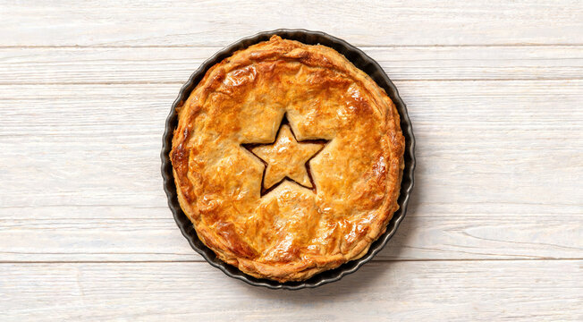 Freshly baked pie with star design on a wooden table