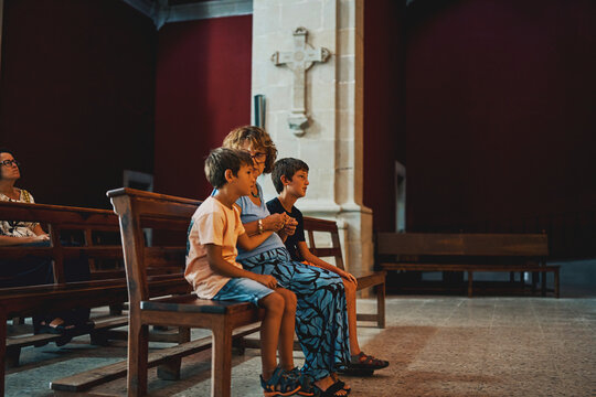 Woman seated with two boys in church pew during worship