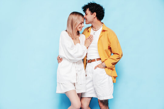 Happy beautiful romantic teenage couple. Smiling handsome caucasian man and young woman in summer clothes posing in studio, hugging sharing emotions, cheerful and happy. Isolated on blue