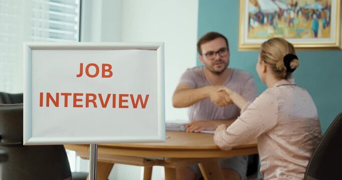 Recruiter and candidate shaking hands during a job interview, representing recruitment, hiring, employment, career opportunities, and professional agreement.