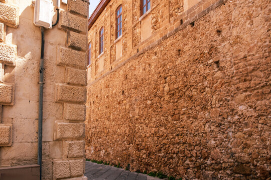 Sunlit stone alley with historic Venetian wall texture in Chania Old Town, Crete, Greece