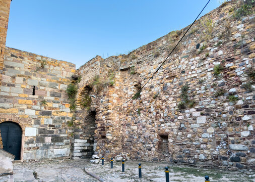 Weathered stone and brick walls, narrow arched passages and sparse plants at Chios Castle in Chios Town, Greece