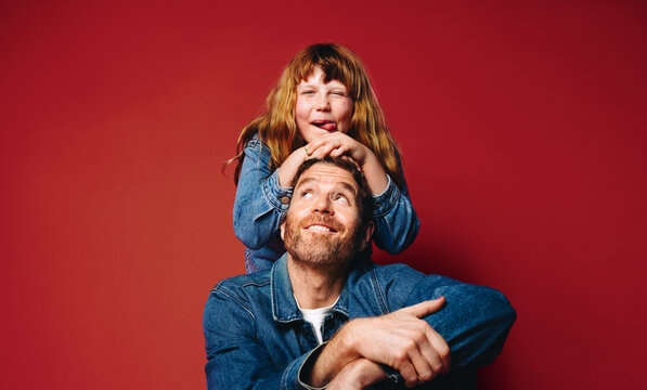Playing together, father and daughter create a happy family portrait with the child on shoulders