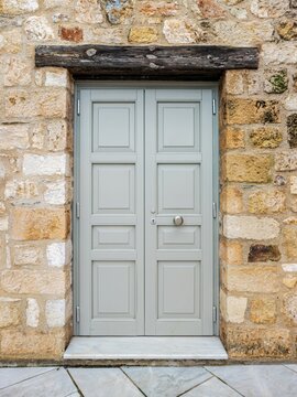 Light grey double door in a rustic stone wall in Monastiraki, Athens, combining weathered masonry, symmetry, and traditional Greek character.
