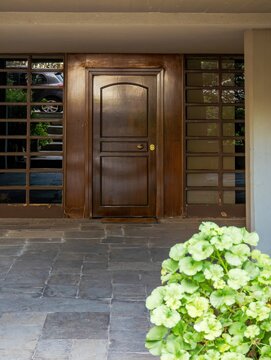 Contemporary Athens house entry with a centered wooden door, glass-block style side panels, and a calm sheltered front approach.