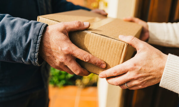 Person receiving a cardboard delivery package at the door