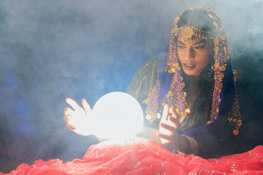 A fortune teller studies a glowing crystal ball
