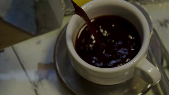 Cafetera italiana sirviendo un caf&eacute; caliente en una taza blanca