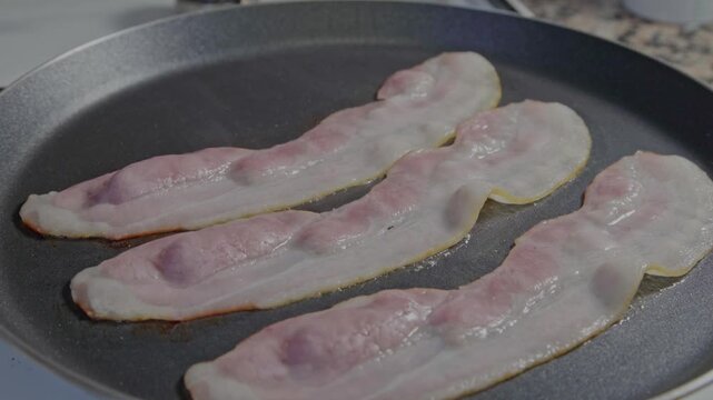 Lonchas de bacon fri&eacute;ndose en una sart&eacute;n