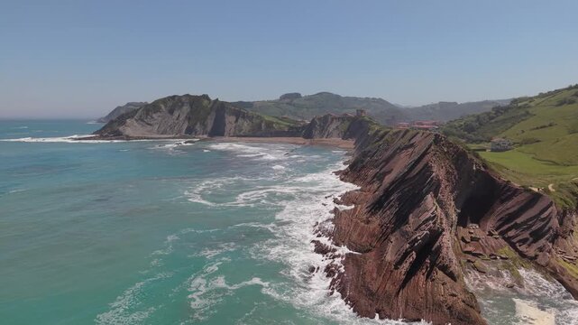Aerial view of layered flysch cliffs and breaking waves