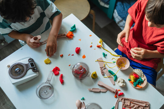 Boy plays with dough and a toy kitchen on a table at home