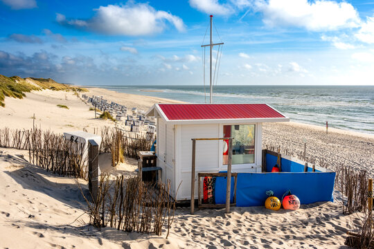 A white lifeguard hut stands on the sandy beach of Sylt island