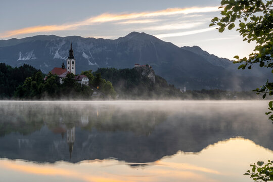 Fog covers Lake Bled with the Pilgrimage Church at sunrise