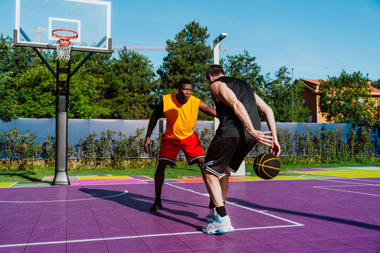 Men play streetball on a colorful outdoor basketball court