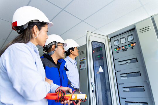 Engineer team examines an electrical control box in a wind farm