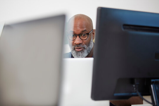 Portrait of astonished man between computer monitors