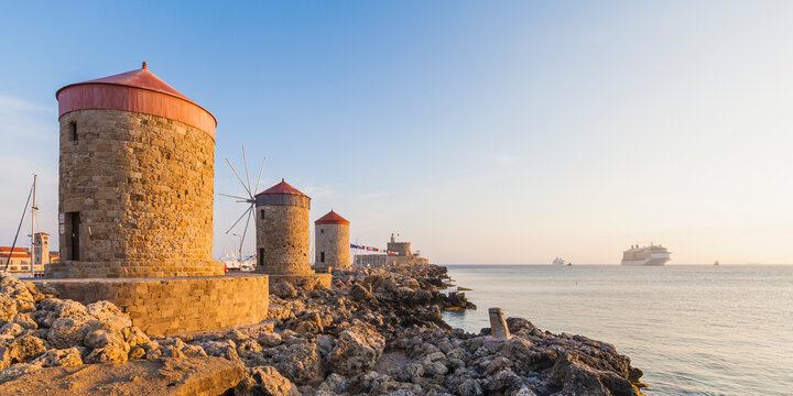 Greece, Rhodes, mole of Mandraki harbour with windmills and cruise ship in background
